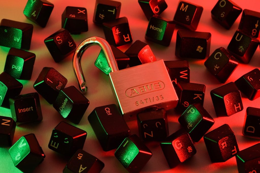 An open padlock resting on scattered keyboard keys lit in red and green, symbolizing digital security vulnerabilities for remote workers
