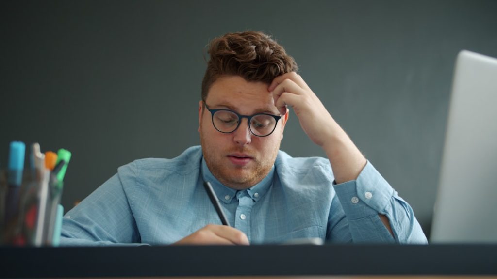 Tired man rubbing his eyes at a desk, illustrating the mental drain caused by distraction and lack of focus during remote work.